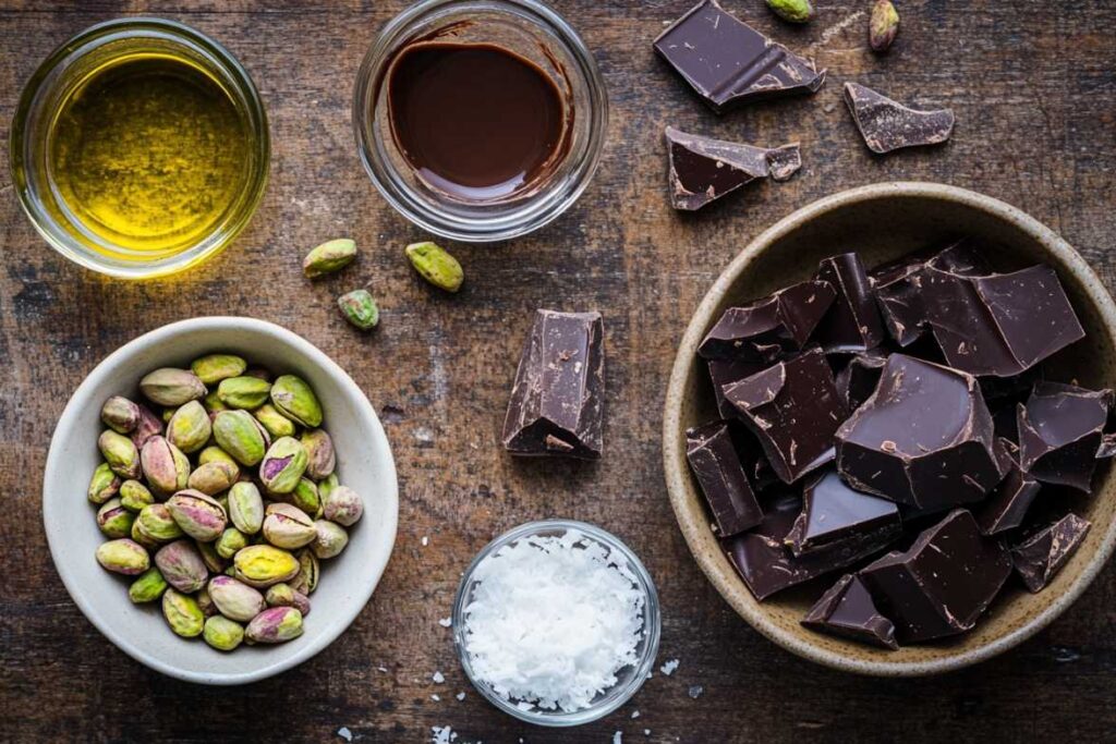 Ingredients for pistachio chocolate bar including pistachios, dark chocolate, coconut oil, and vanilla.