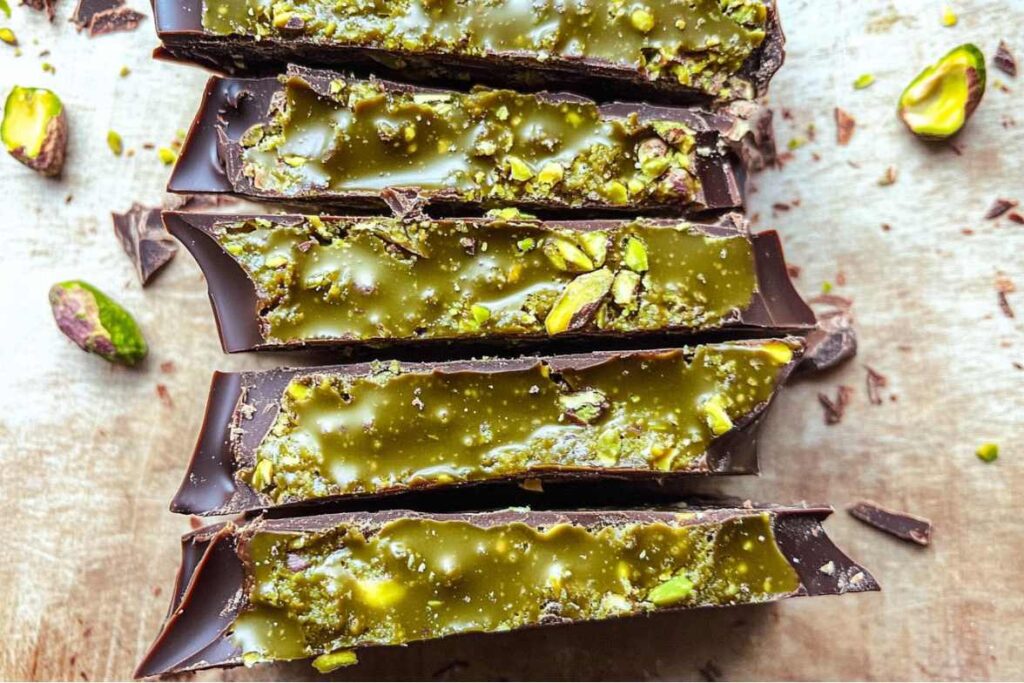 Close-up of pistachio chocolate bar with a layer of glossy green pistachio filling and chopped pistachios sprinkled on top.