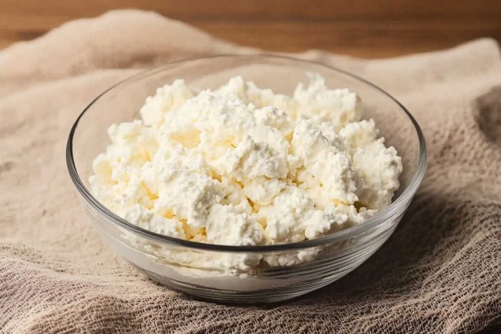 A bowl of creamy cottage cheese on a textured cloth.