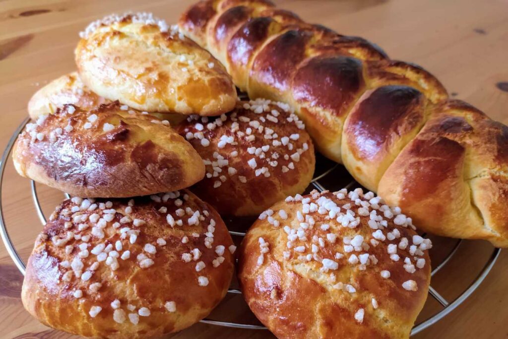 Freshly baked golden brioche rolls and loaf on a cooling rack