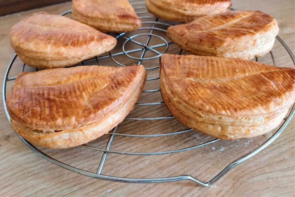 Golden-brown Chausson aux Pommes cooling on a wire rack