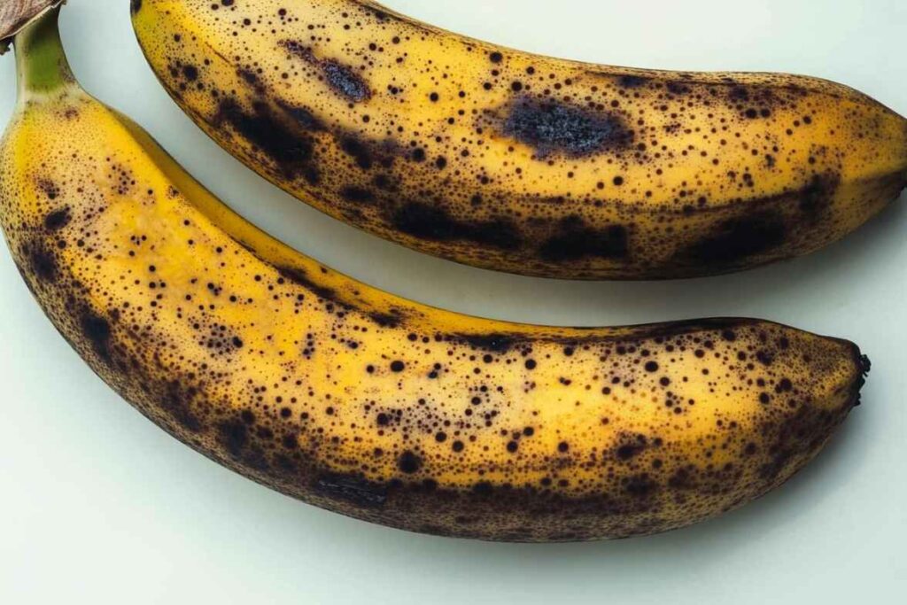 Two overripe bananas with black spots on their yellow peel.