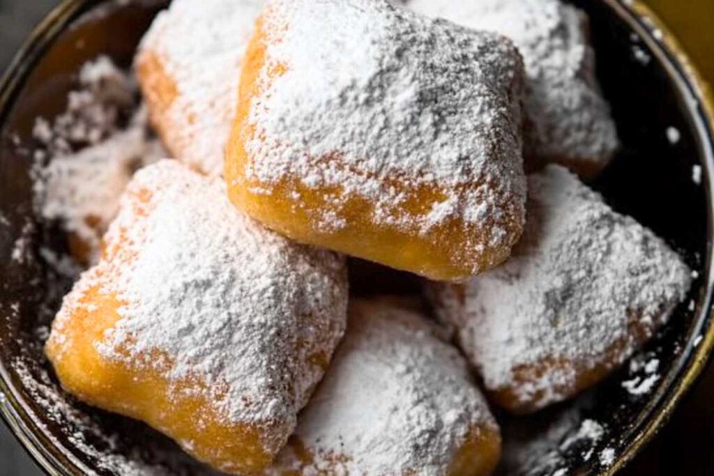 Classic New Orleans beignets dusted with powdered sugar in a bowl