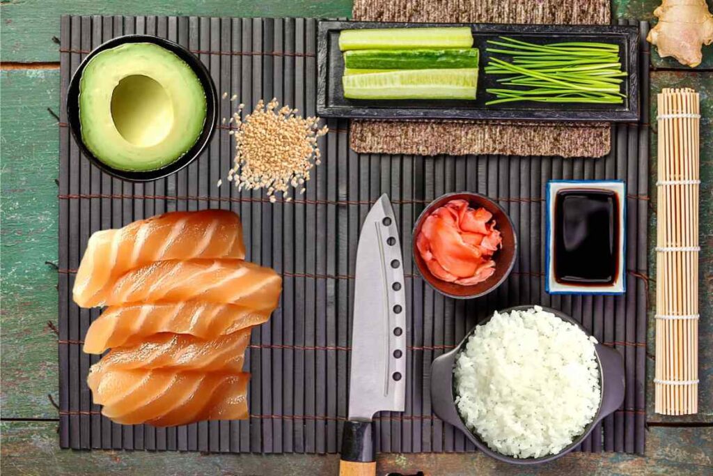 Fresh ingredients for making Alaskan roll sushi neatly arranged on a sushi mat.