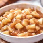 A bowl of Homemade Apple Pie Filling, featuring tender apple chunks coated in a rich, cinnamon-spiced sauce.