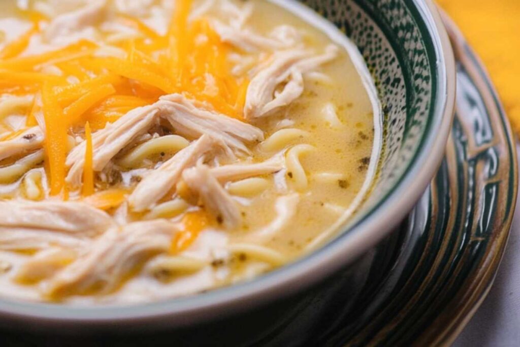 Crack Chicken Noodle Soup with shredded chicken and melted cheddar cheese