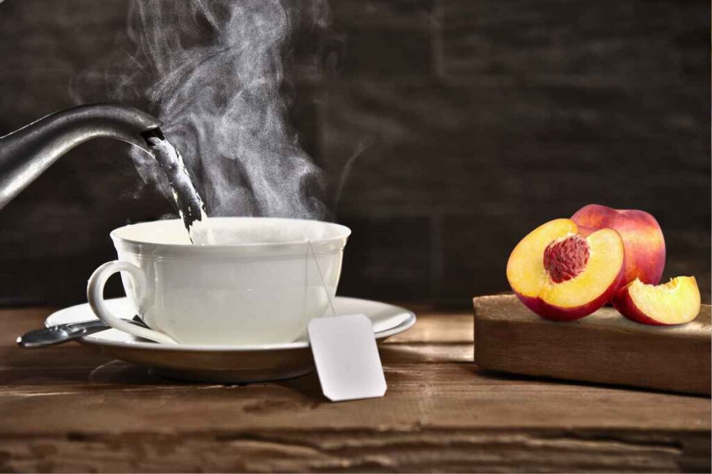 A steaming cup of peach tea with fresh peach slices on a wooden table.