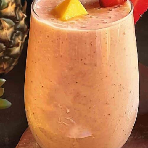 A creamy and refreshing Bahama Mama Tropical Smoothie served in a chilled glass, garnished with a fresh strawberry and pineapple chunk.